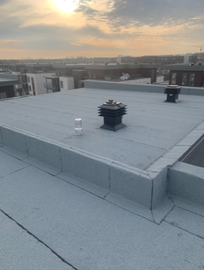 Un toit avec deux cheminées et une vue sur une ville.