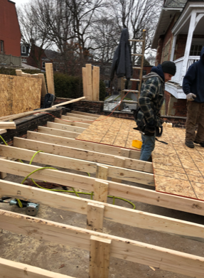 Un homme se tient debout sur une terrasse en bois en construction.