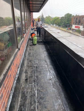 Un homme se tient sur un balcon à côté d'un bâtiment en briques.