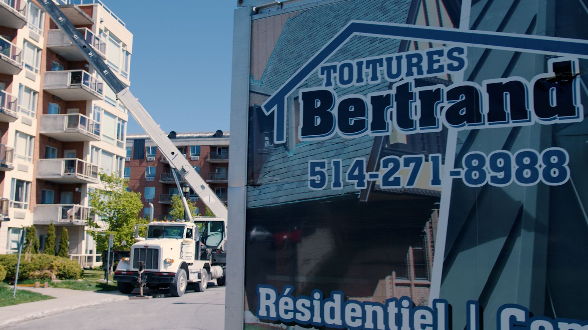 Un camion est garé devant un panneau indiquant toitures bertand