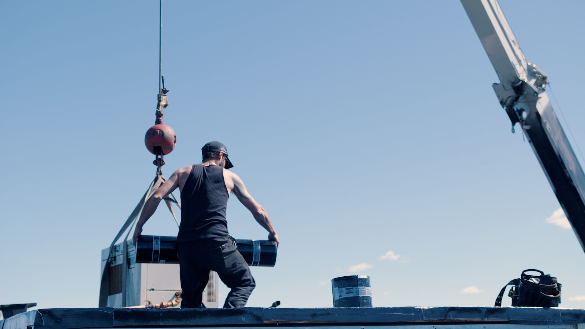 Un homme se tient debout sur un bateau avec une grue en arrière-plan.