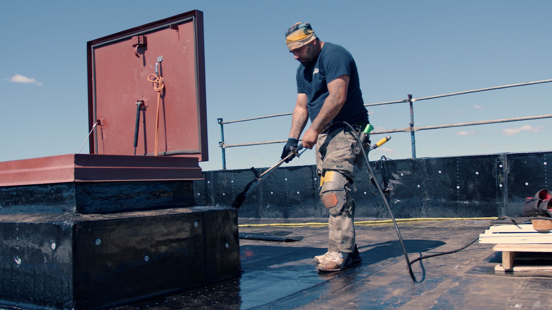 Un homme arrose un toit avec un tuyau.