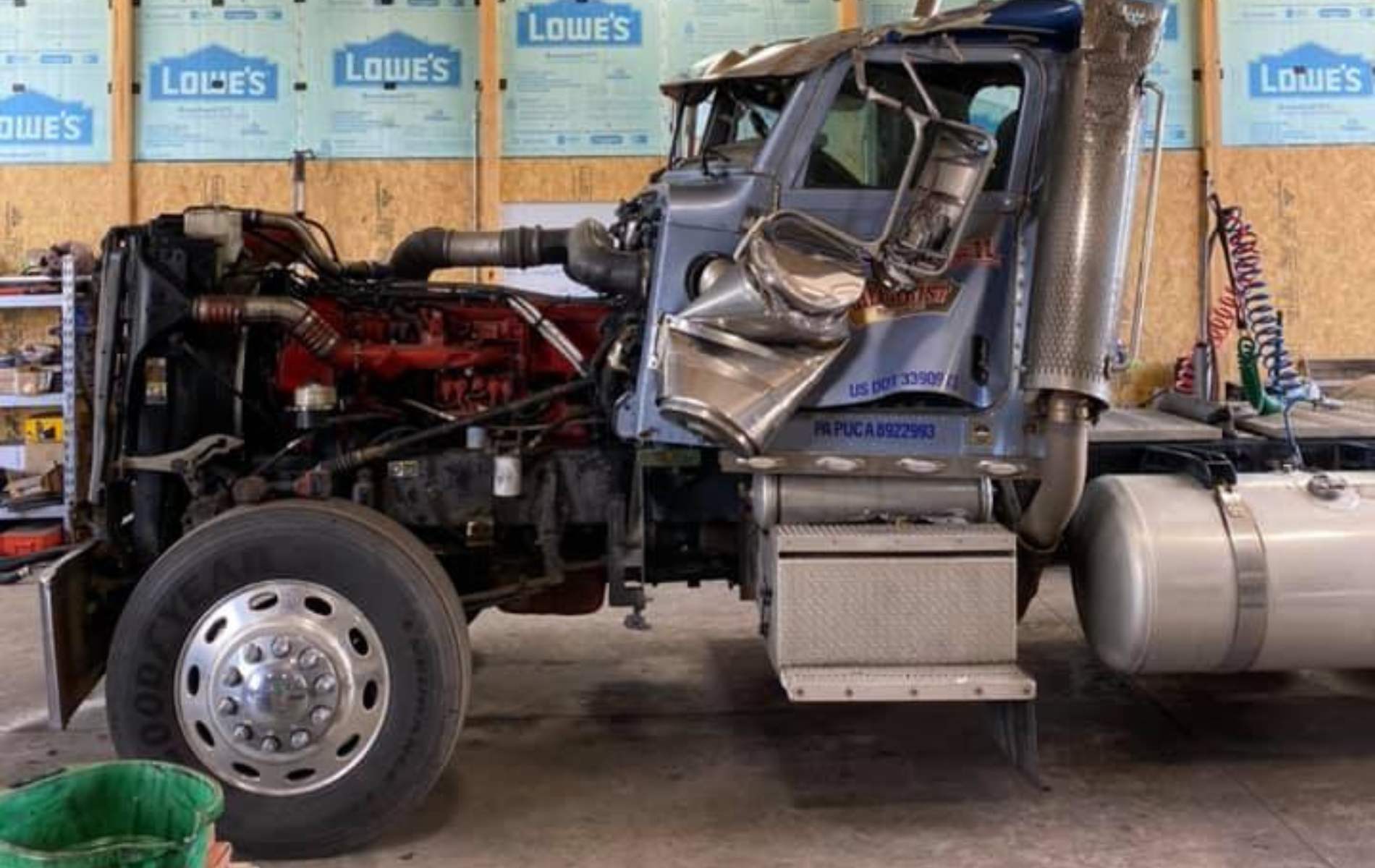 A semi truck is being repaired in a garage.