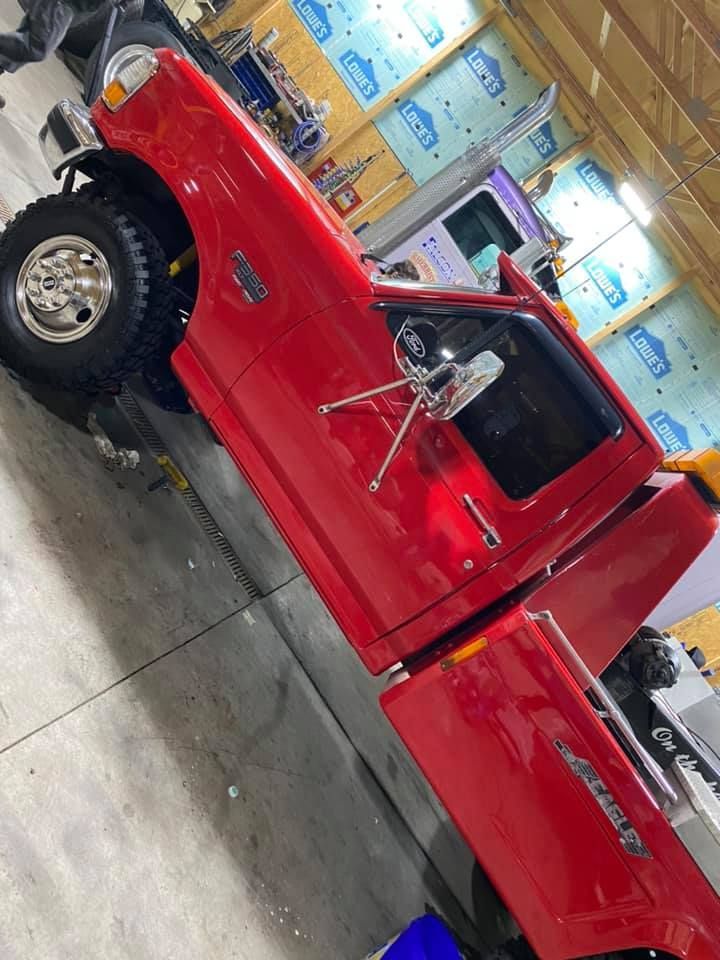 Red Ford pickup truck, with large tires, indoors, angled view.