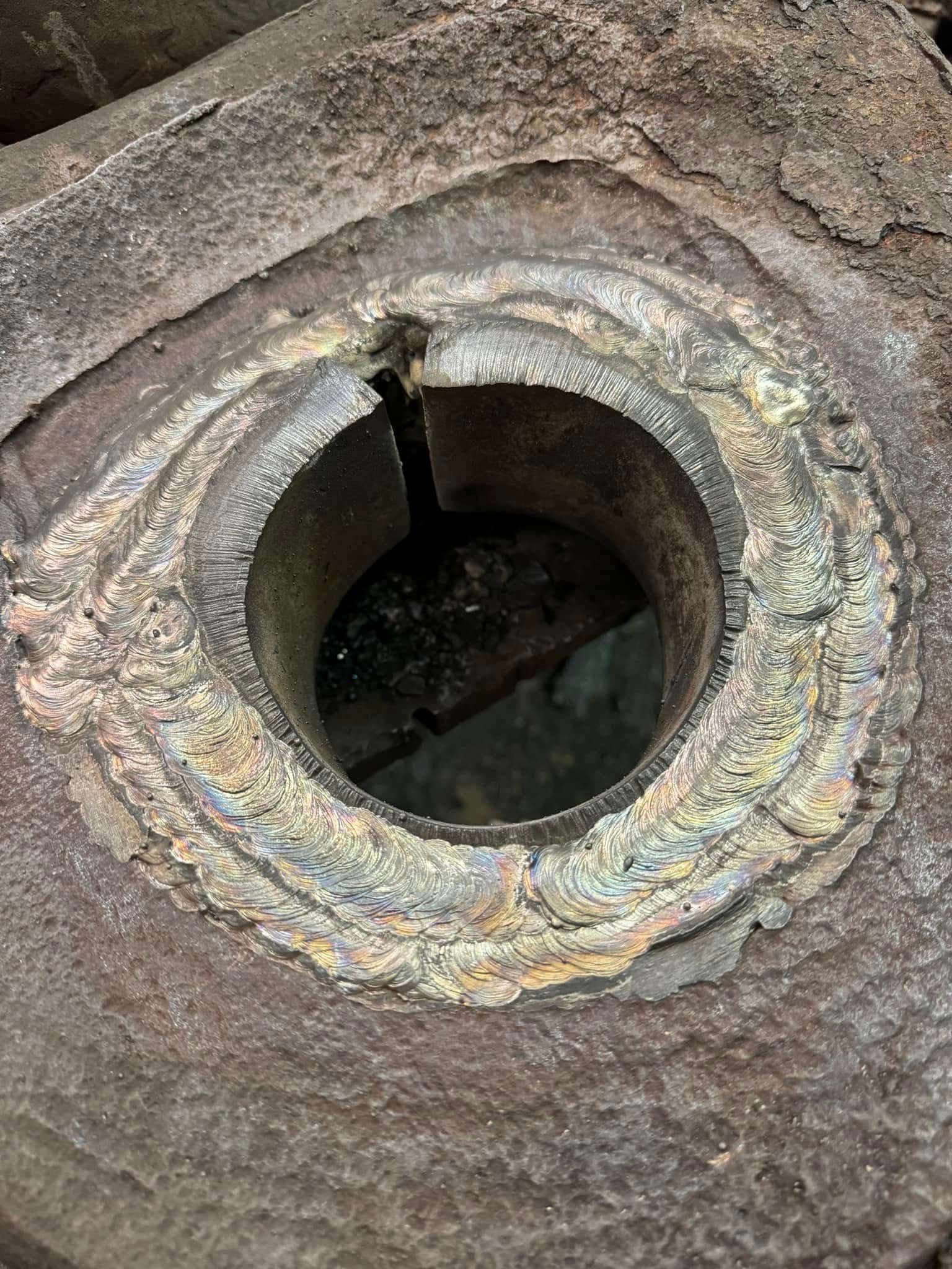 Close-up of a rusty, metal cylinder with a crack, inside a square-like frame, and a circular opening.
