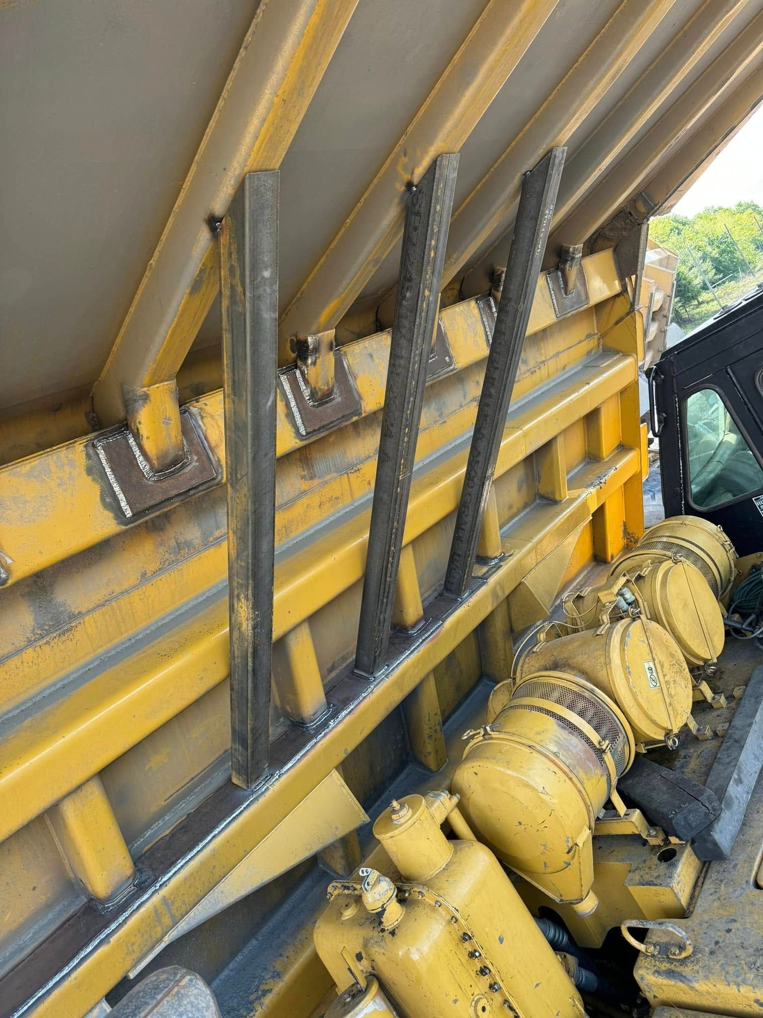 Yellow dump truck bed interior with steel supports.