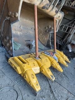 Yellow excavator bucket teeth and supports.