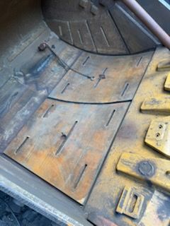 Yellow, worn metal interior, possibly of a heavy machine, with bolted plates and dark seams.