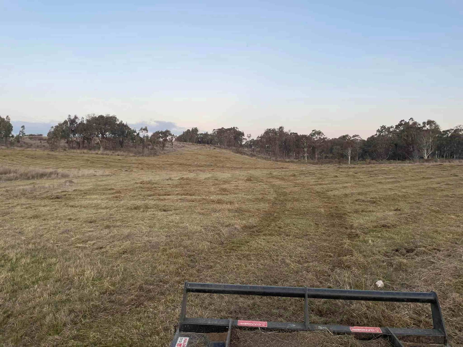 Cutting Grass in A Field with Trees — St Elmo Contracting in Peelwood, NSW