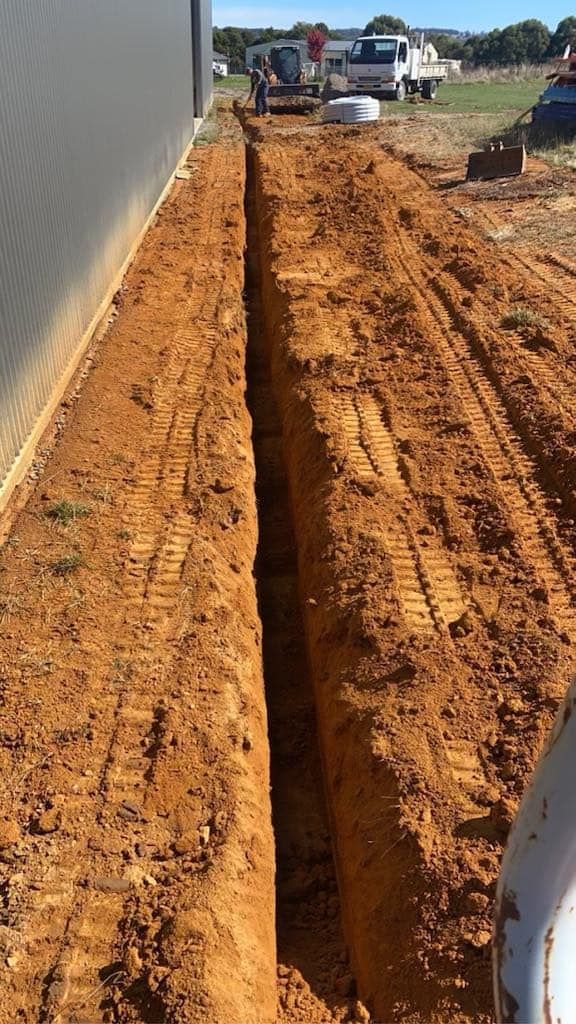 Digging a Large Pile of Land in Front of A Building — St Elmo Contracting in Peelwood, NSW