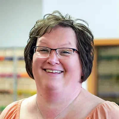 A woman wearing glasses is smiling for the camera.