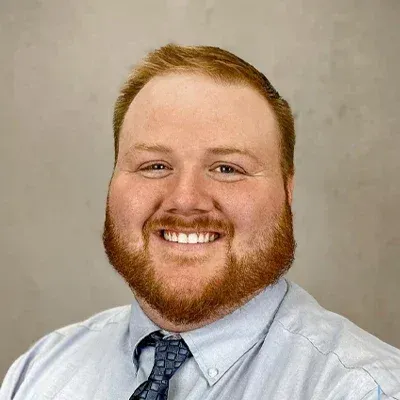 A man with a beard and tie is smiling for the camera.