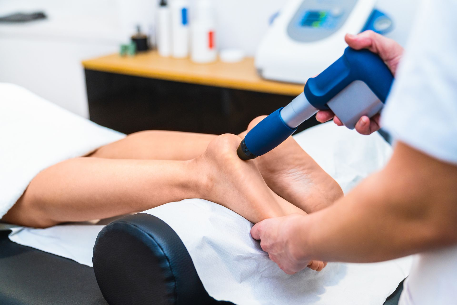 A woman is getting a shockwave treatment on her leg.