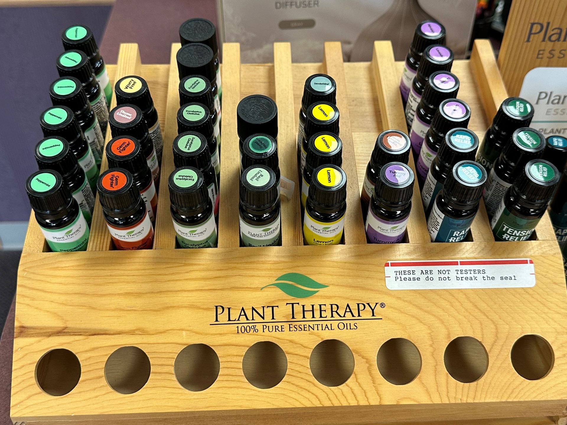 A display of plant therapy essential oils in a wooden holder