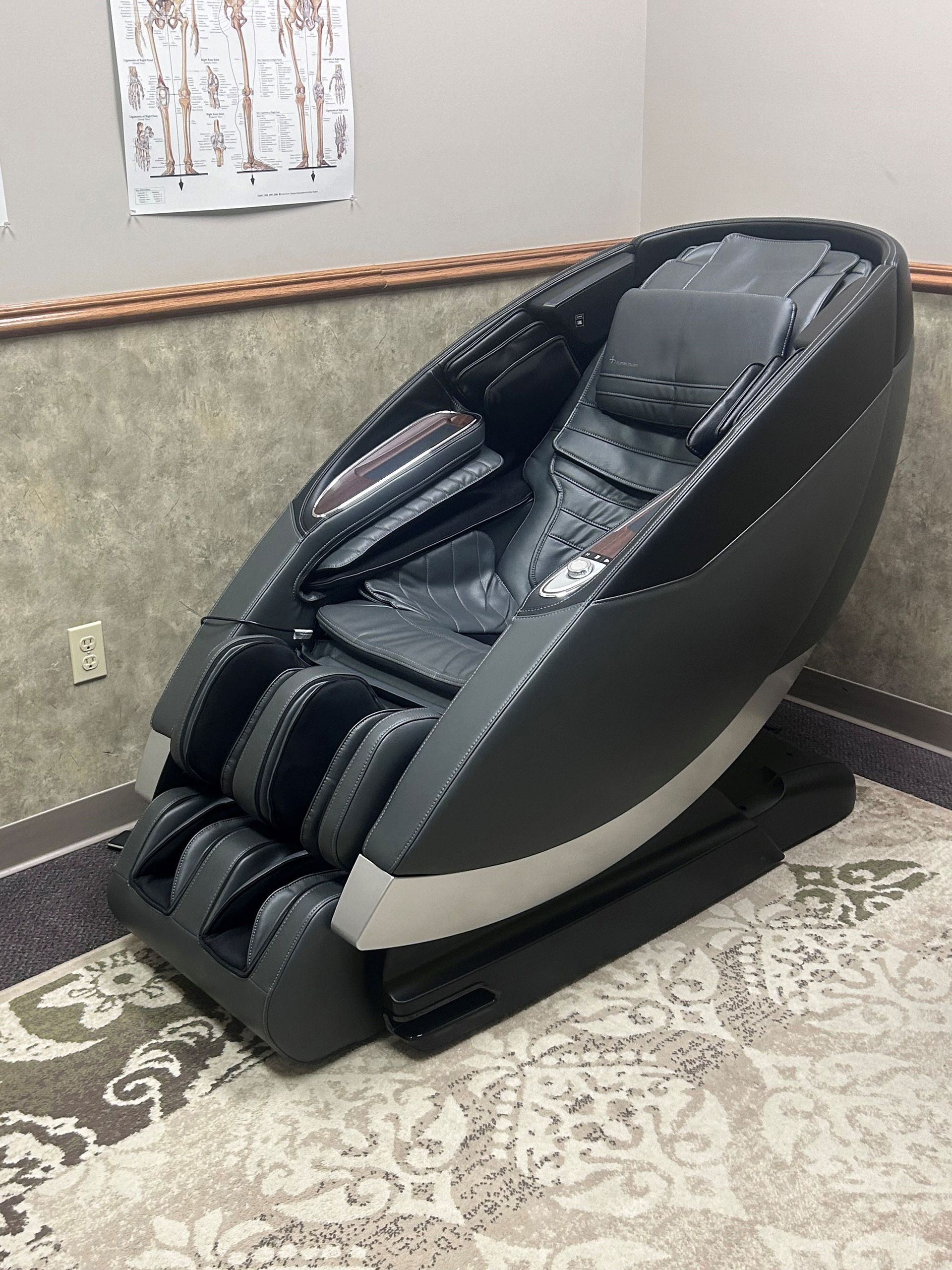 A black massage chair is sitting on a rug in a room.