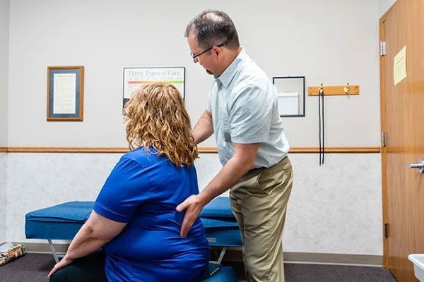 A man is examining a woman 's back in a room.