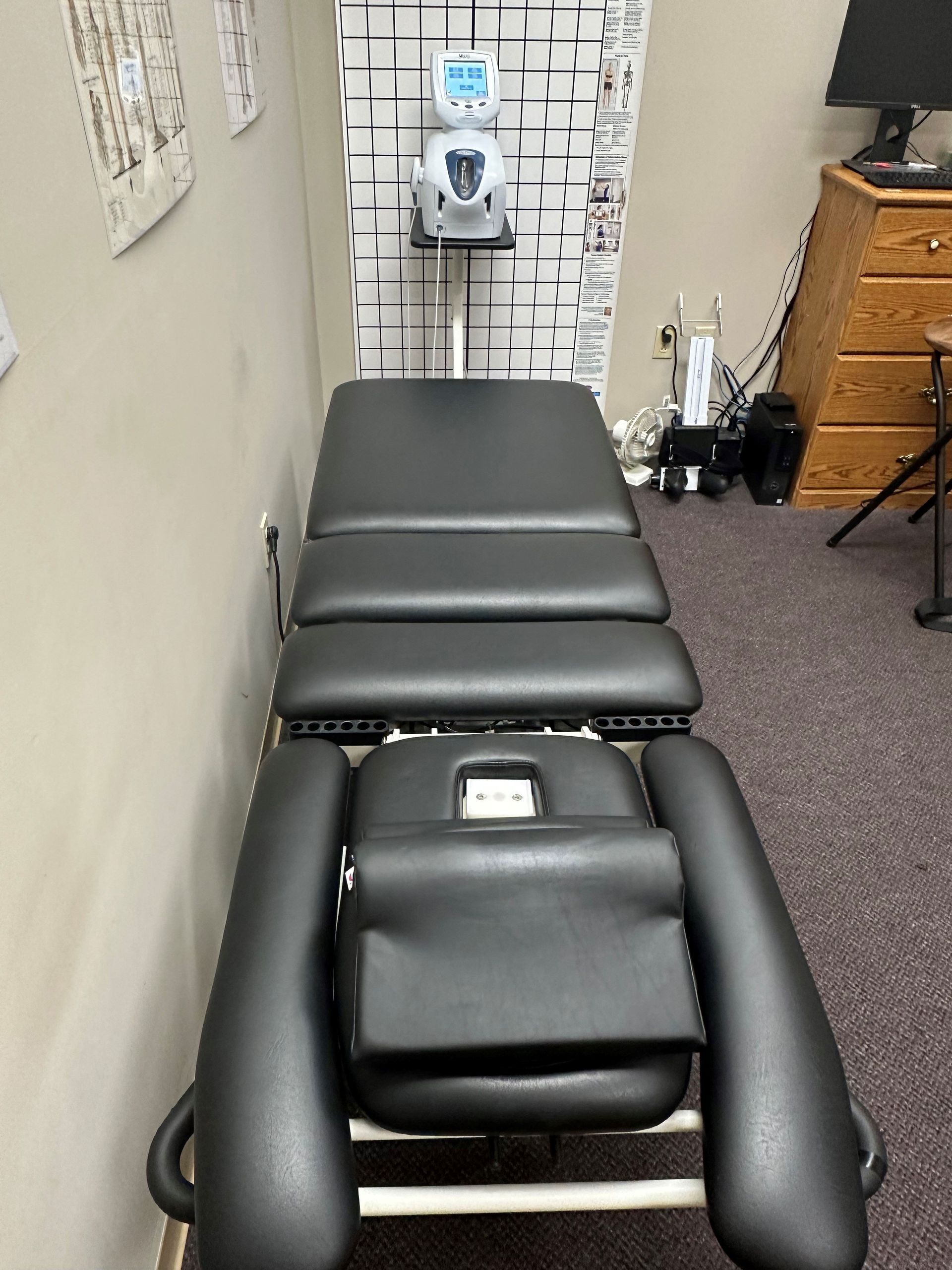 A black massage table is sitting in a room next to a computer.