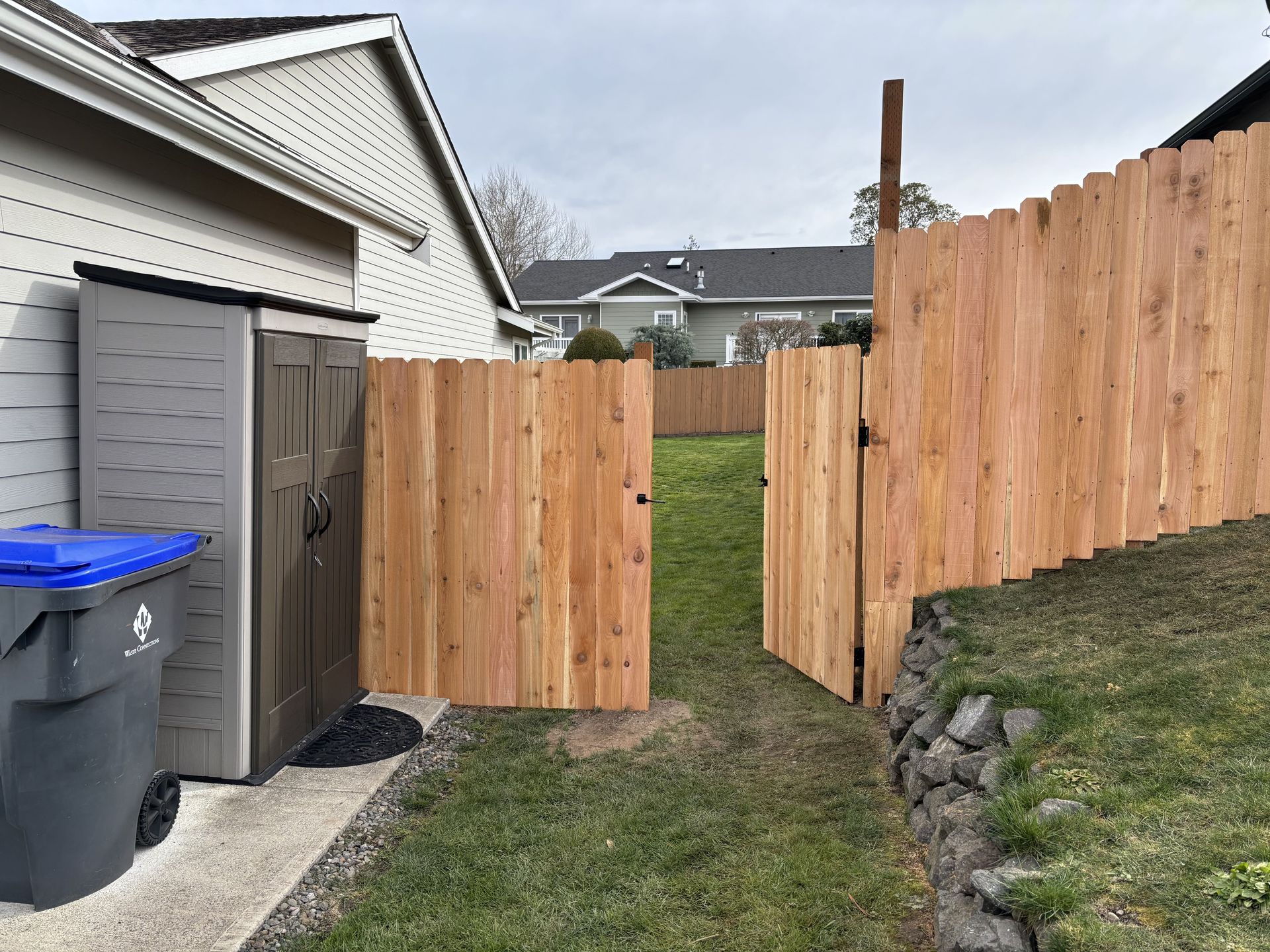 A wooden fence with a gate in the backyard of a house.