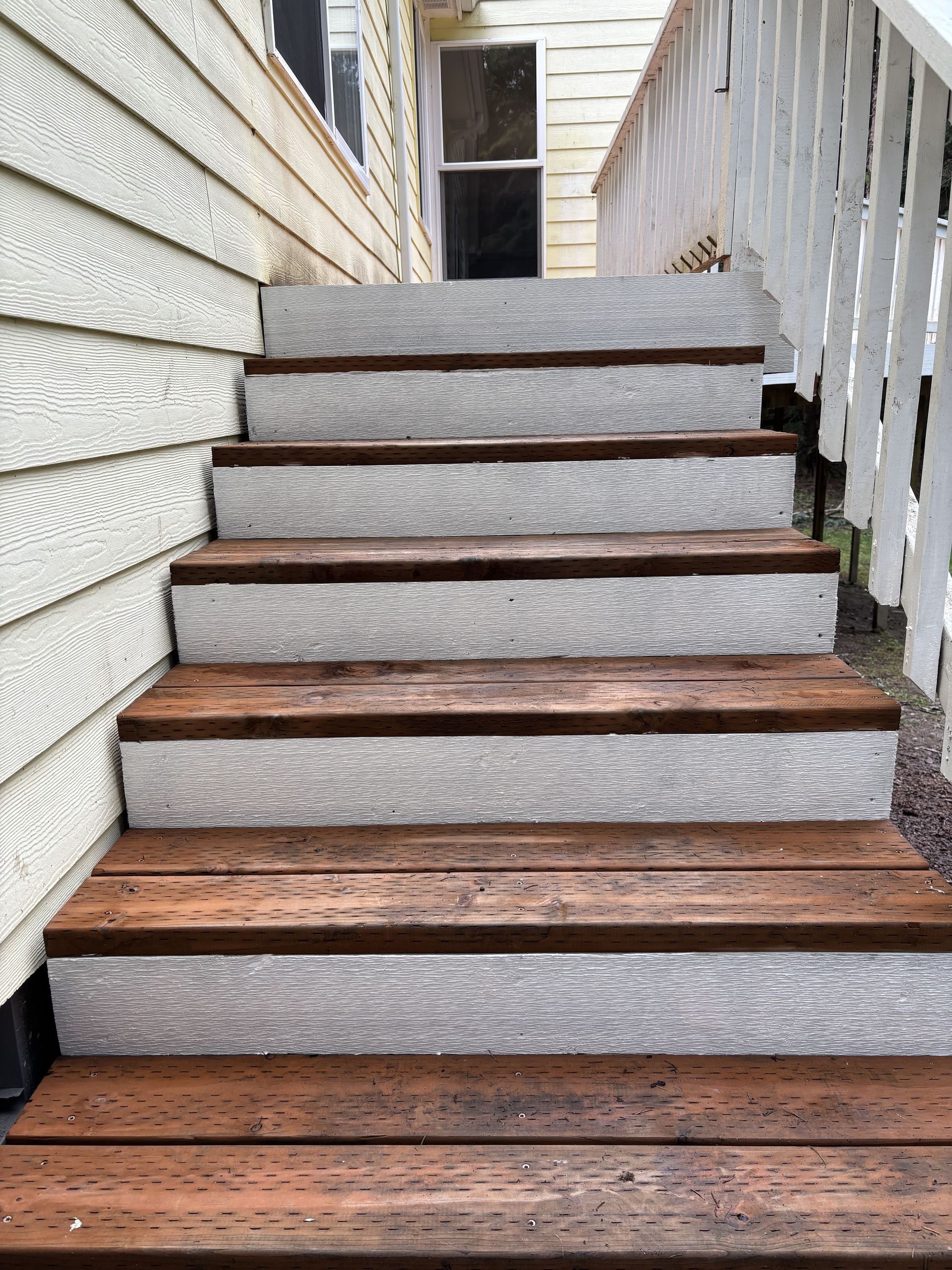 A set of wooden stairs leading up to a white house