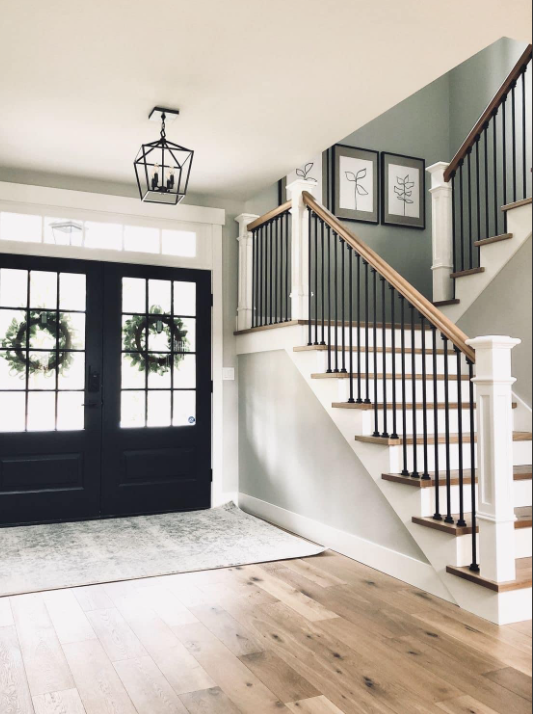 A staircase featuring a modern, dark brown accent wall with a geometric grid of trim, alongside white walls and railing.