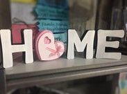 The word home is made of wood and is sitting on a table.