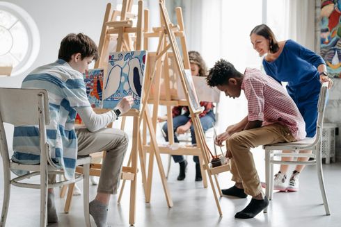 A group of people are painting on easels in a room.