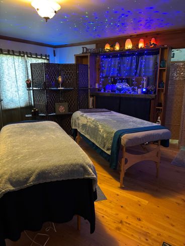 Two massage tables in a dimly lit room with star-like ceiling lights and blue accents.