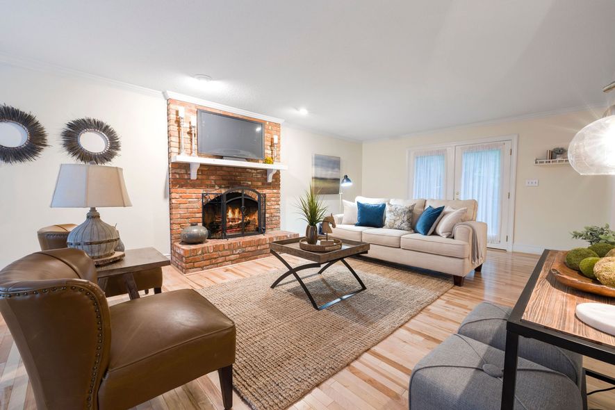 Bright living room with fireplace, beige sofa, glass coffee table, and warm neutral decor