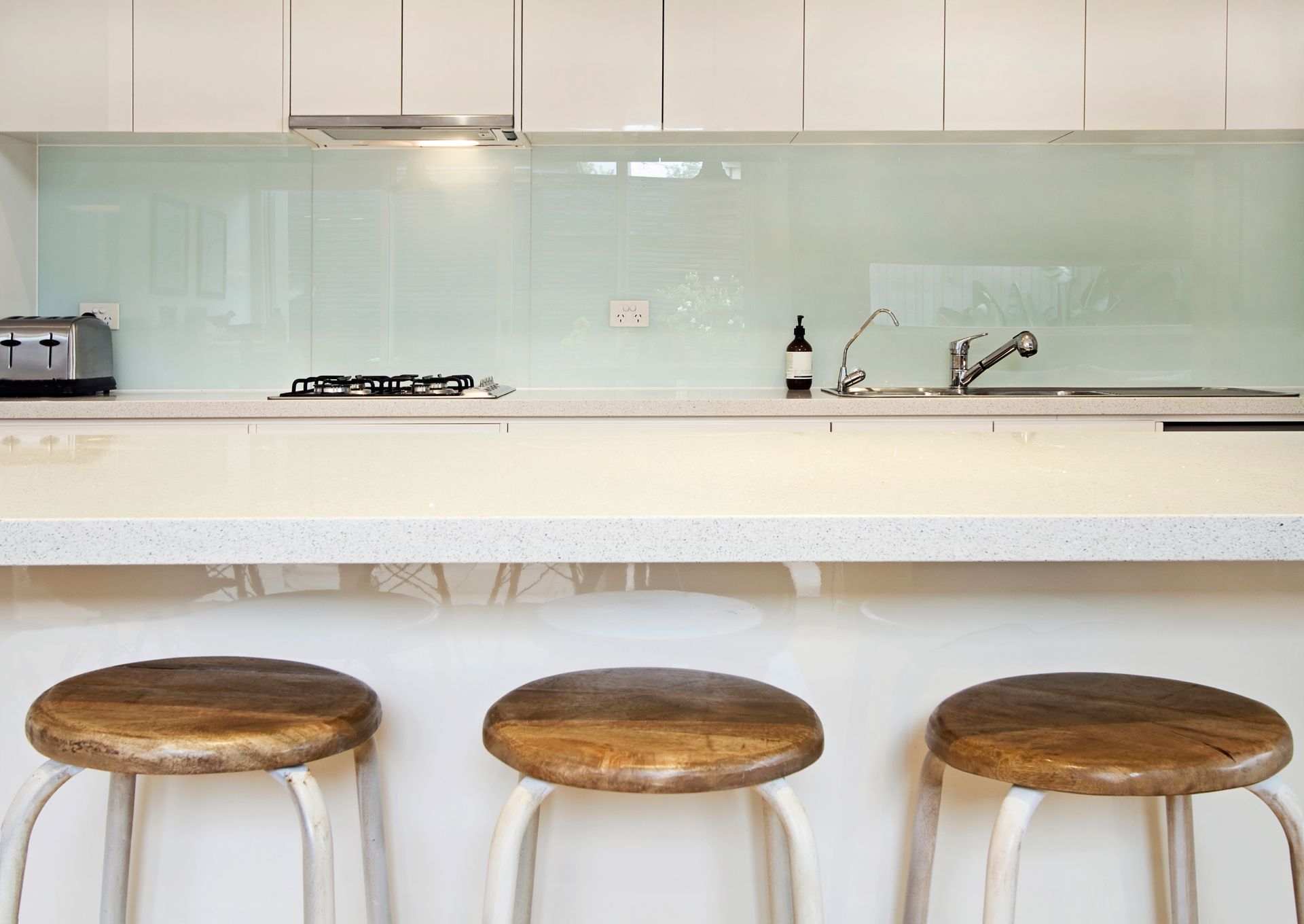 Stylish kitchen with glass splashback, breakfast bench, and stools.