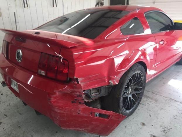 A red ford mustang with a damaged rear end