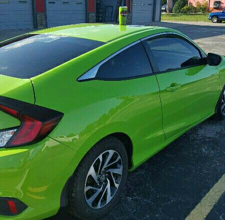 A green honda civic coupe is parked in a parking lot.