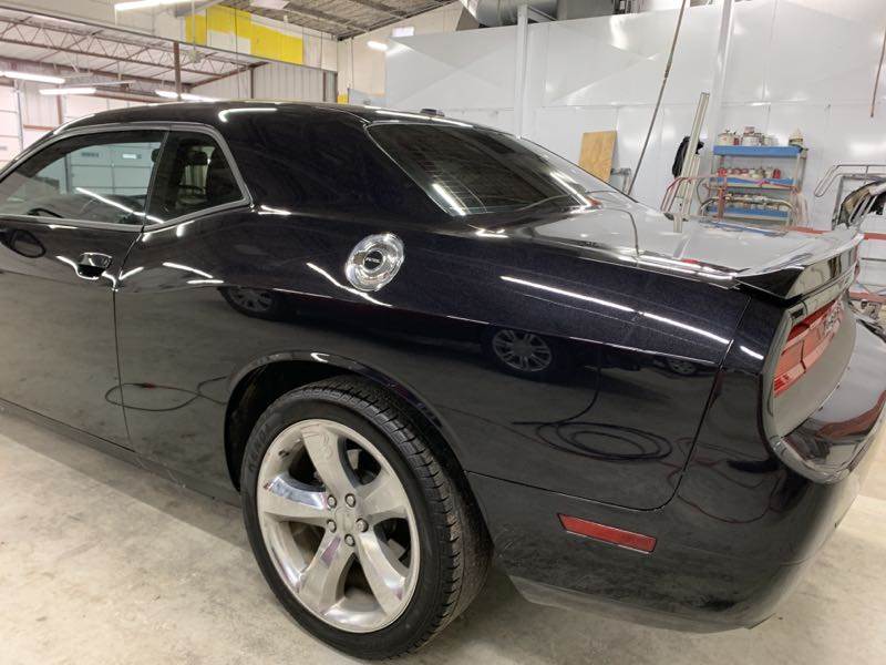 A black dodge challenger is parked in a garage.