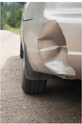 A car with a damaged bumper is parked on the side of the road.