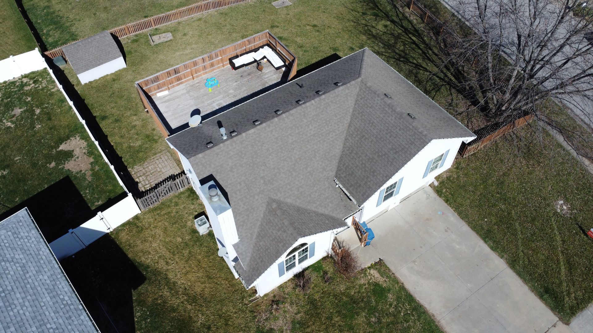 An aerial view of a house with a gray roof and a driveway.