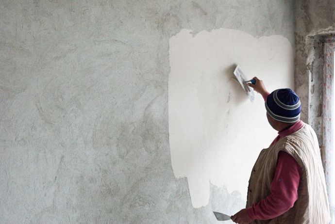 man plastering a grey wall