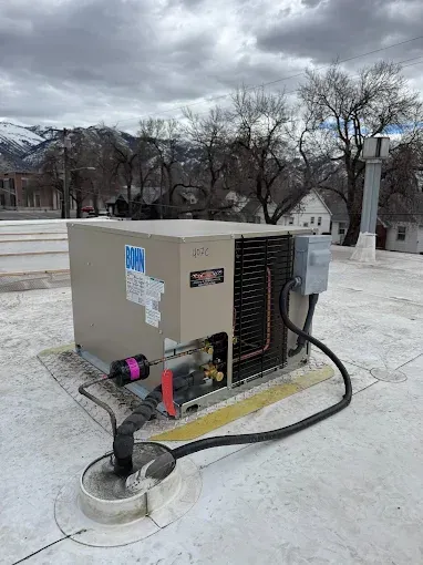 An air conditioner is sitting on top of a white roof.
