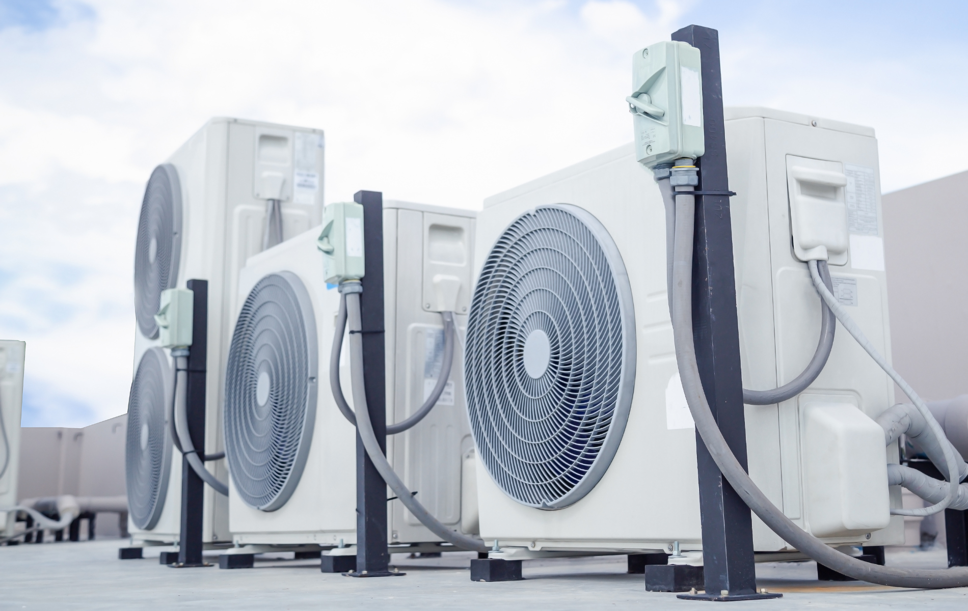 A row of air conditioners are sitting on top of a roof.