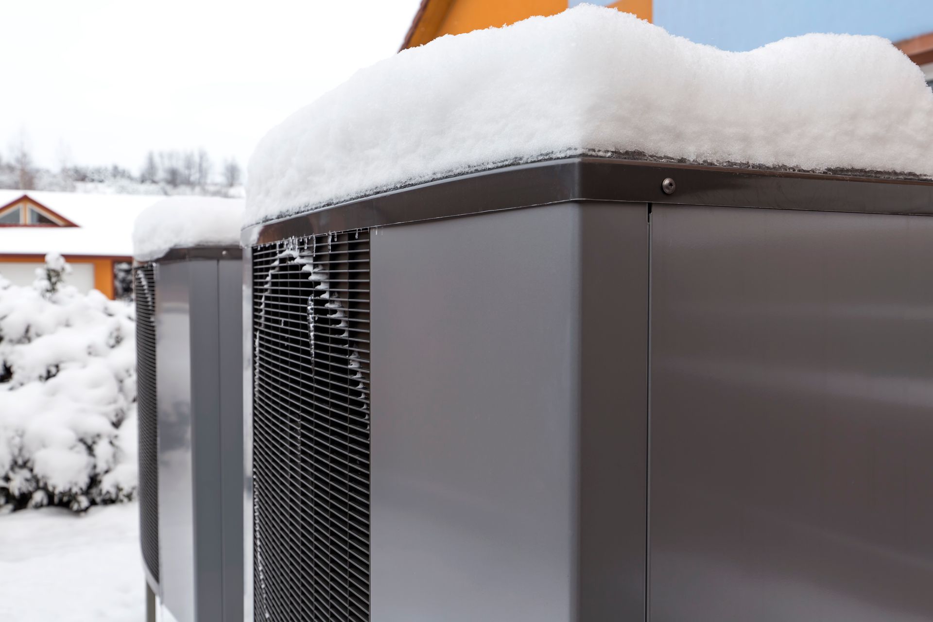 Air source heat pump units covered in snow. Outdoors, winter.