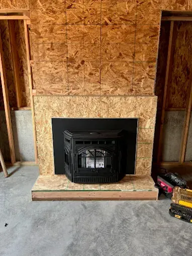A fireplace is being built in a room in a house under construction.