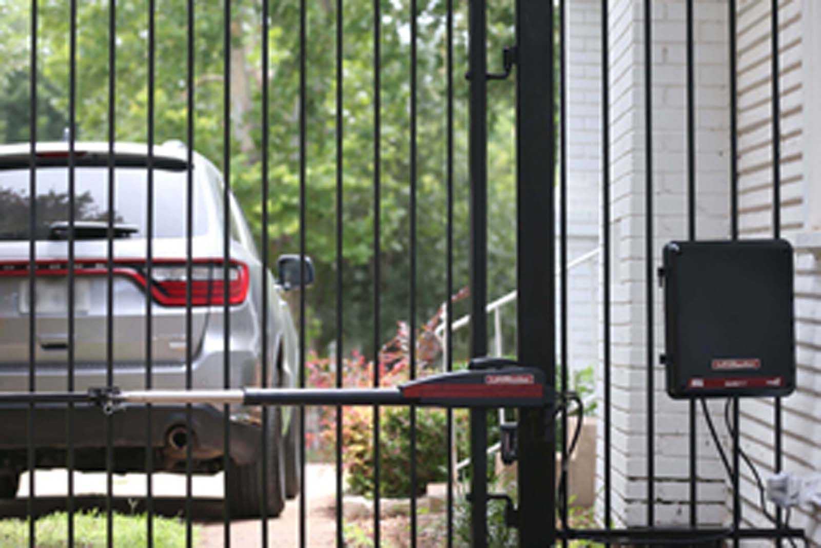 A car is parked in front of a gate that is open.