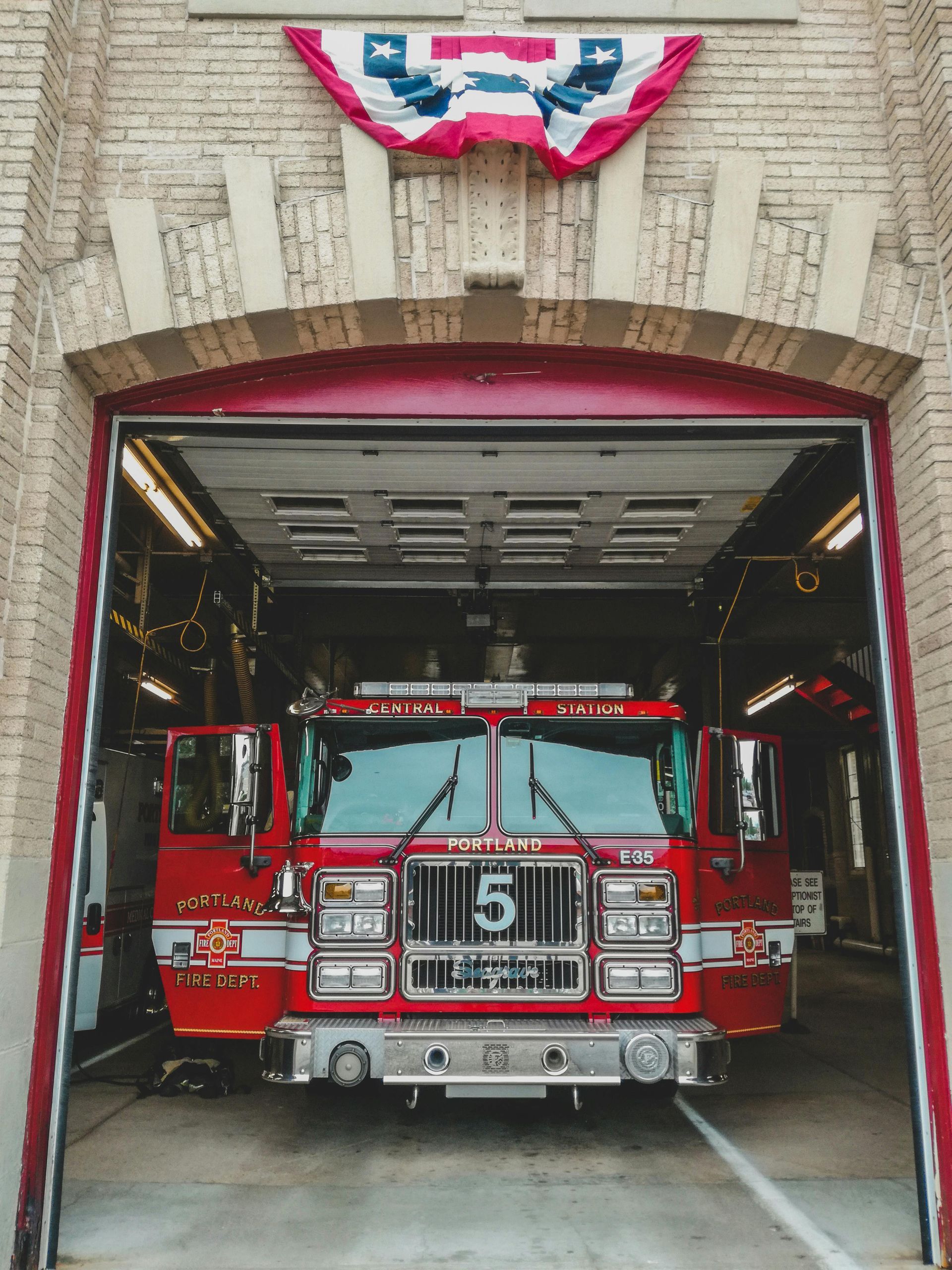 A red fire truck with the number 5 on the front is parked in a garage