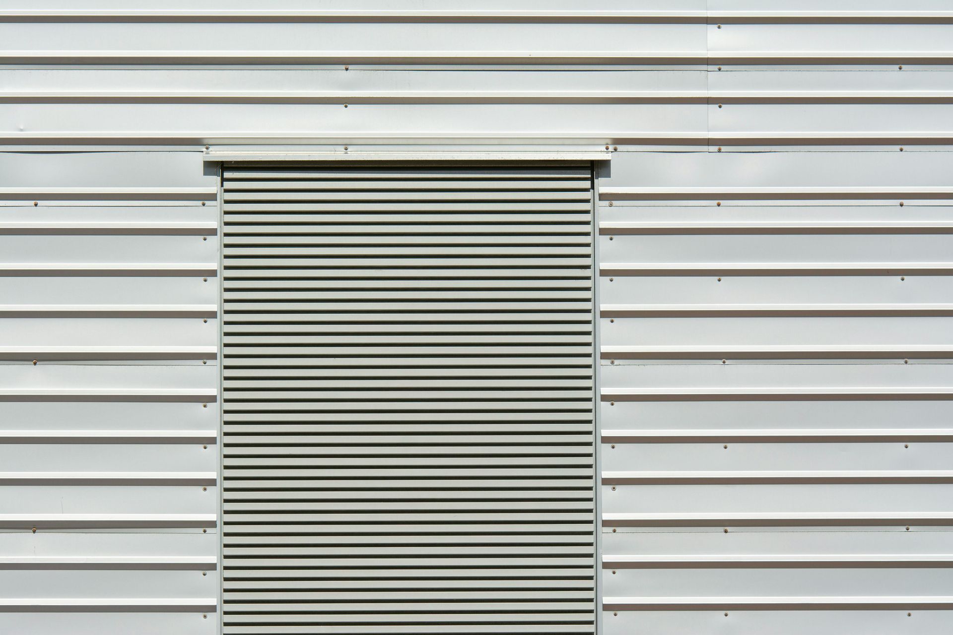 A close up of a metal wall with a roller shutter on it.