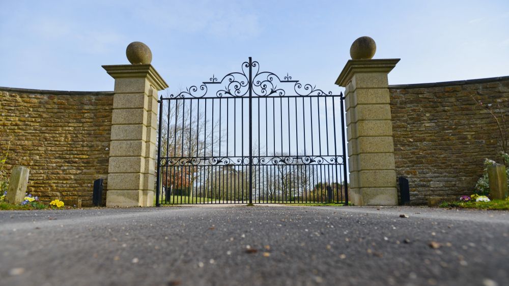 A large wrought iron gate is surrounded by a stone wall.