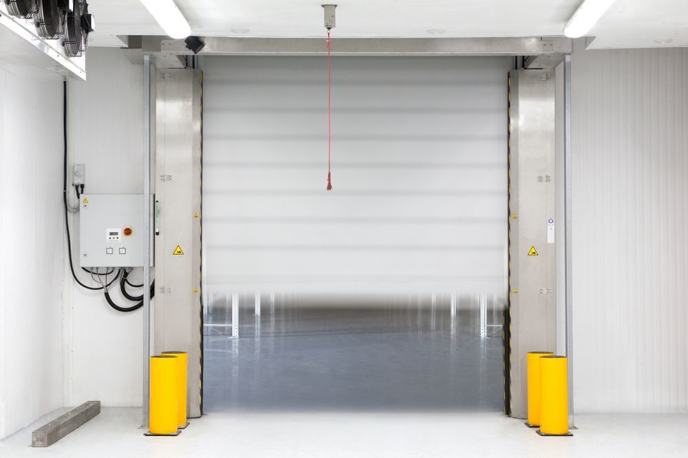 A white roller door is open in a warehouse.
