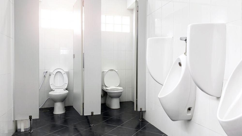 A public restroom with two toilets and two urinals.