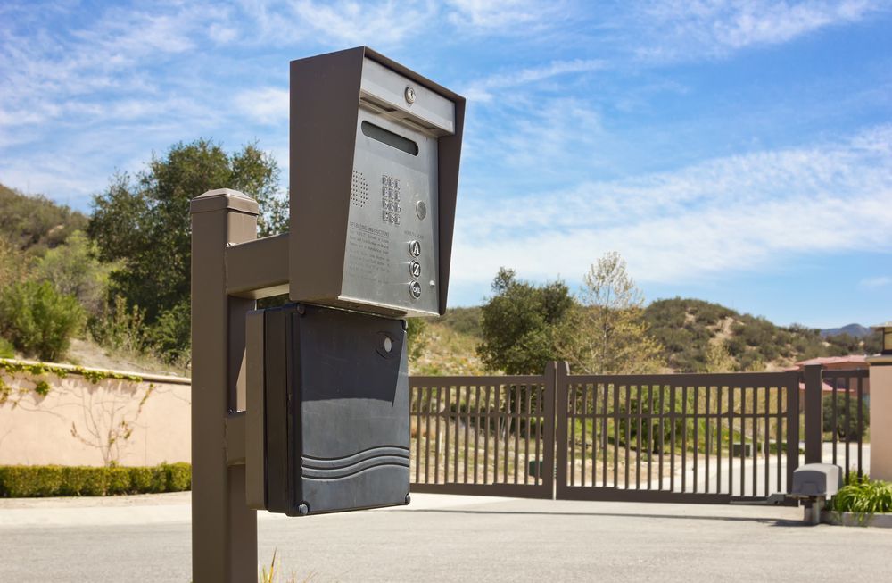 A mailbox is sitting next to a gate in front of a fence.