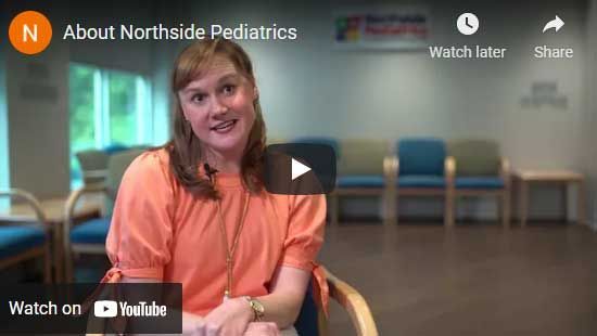 Woman in orange shirt in a pediatric office setting, smiling, promoting Northside Pediatrics.