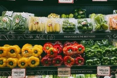 Produce display of colorful bell peppers and packaged vegetables on a store shelf.