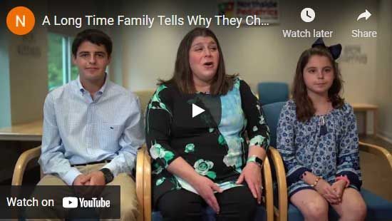 Family sitting in chairs; woman in center speaks, children on either side. Neutral-toned room; YouTube video.