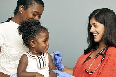 Child getting a vaccine from a medical professional, with parent present.